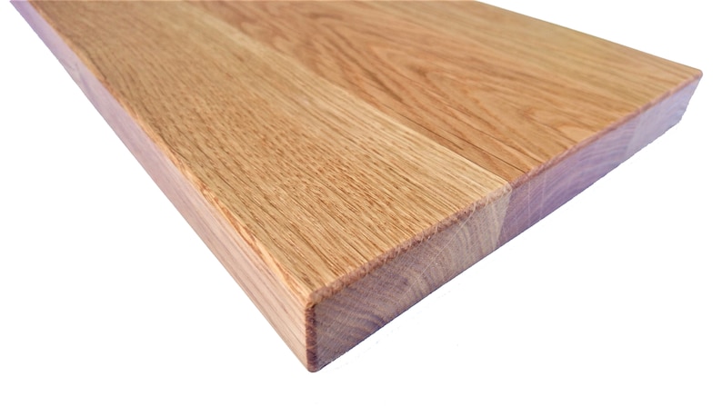 Pu&ograve; includere: Primo piano del bordo di un piano di lavoro in legno marrone chiaro. La venatura del legno &egrave; visibile e la superficie &egrave; liscia.