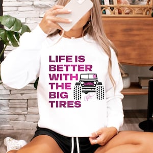 May include: White sweatshirt with a pink graphic of a Jeep with the text "Life is better with the big tires".