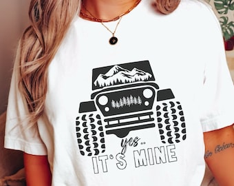 May include: White t-shirt with a black graphic of a jeep with mountains in the background. The text "yes... it's mine" is printed below the jeep.