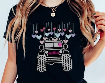 May include: Black t-shirt with a graphic of a Jeep decorated with colorful hearts. The Jeep has a pink and white flower on the hood.