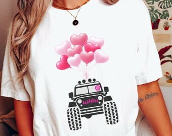 May include: White t-shirt with a black Jeep silhouette and pink heart balloons. The Jeep has a pink "LOVE" written on the front grill.