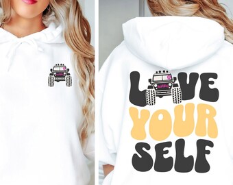 May include: White hooded sweatshirt with a black and white jeep graphic on the front and the text "LOVE YOURSELF" in yellow and black on the back.