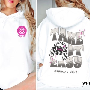 K&ouml;nnte beinhalten: Wei&szlig;er Hoodie mit einem rosafarbenen Reifen-Motiv auf der linken Brust und dem Text "Take It Easy Offroad Club" auf der R&uuml;ckseite. Die Grafik auf der R&uuml;ckseite zeigt au&szlig;erdem einen grauen Jeep.