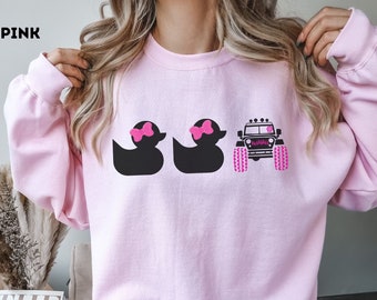 May include: Light pink sweatshirt with a graphic of two black rubber ducks with pink bows and a black Jeep with pink wheels. The text "LIGHT PINK" is in the top left corner of the image.