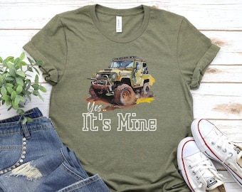 May include: Green t-shirt with a graphic of a yellow jeep driving through dirt. The text "Yes... It's Mine" is printed below the jeep.
