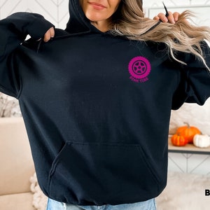 K&ouml;nnte beinhalten: Schwarzer Hoodie mit einem rosafarbenen Reifen-Motiv und dem Text "Pink Tire" auf der Vorderseite.