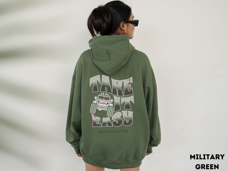 K&ouml;nnte beinhalten: Gr&uuml;ner Kapuzenpullover mit dem Text "Take It Easy" und einer Grafik eines Jeeps auf der R&uuml;ckseite. Der Text "Offroad Club" ist unter der Grafik gedruckt.