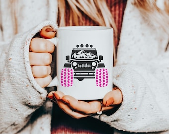 May include: White ceramic mug with a black silhouette of a jeep with pink tires and a mountain scene in the background.