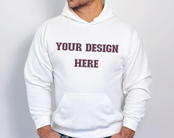 Może przedstawiać: Biała bluza z kapturem z przednią kieszenią i napisem "YOUR DESIGN HERE" w bordowej czcionce. Bluza ma długie rękawy i kaptur ze sznurkiem. Model ma na sobie niebieskie dżinsy.
