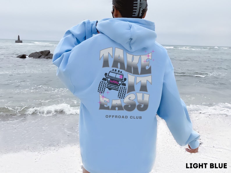 K&ouml;nnte beinhalten: Hellblauer Hoodie mit einem Grafikdruck eines Jeeps und dem Text "Take It Easy Offroad Club".