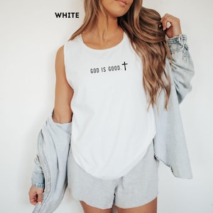 May include: White sleeveless shirt with the text "GOD IS GOOD" and a cross symbol in black. The word "WHITE" is in the upper left corner. The shirt is part of a casual clothing set.