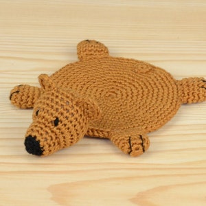 May include: A brown crocheted bear-shaped coaster with black eyes and a black nose.