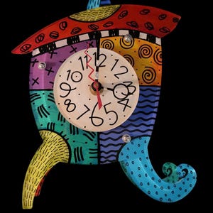 May include: A colorful, whimsical clock shaped like a house with a clock face featuring black numbers on a white background. The clock has a red hour hand and a black minute hand. The house is painted in a variety of colors, including red, yellow, blue, green, and purple. The house has a yellow and blue roof and a blue and green base.