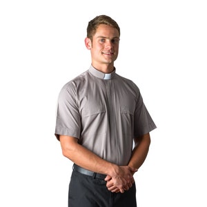 May include: A grey short-sleeved clergy shirt with a white clerical collar. The shirt has a single chest pocket and a button-up front.