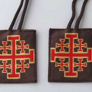 May include: Two brown fabric keychains with red and gold embroidered Jerusalem crosses.