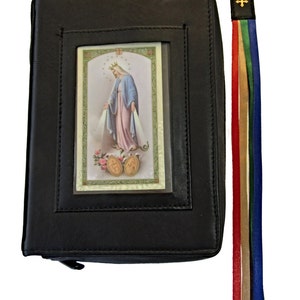 Puede incluir: Cubierta de libro de cuero negro con cierre de cremallera y una ventana transparente que muestra una imagen religiosa de la Virgen María. Un marcapáginas de cinta multicolor está unido a la cubierta.