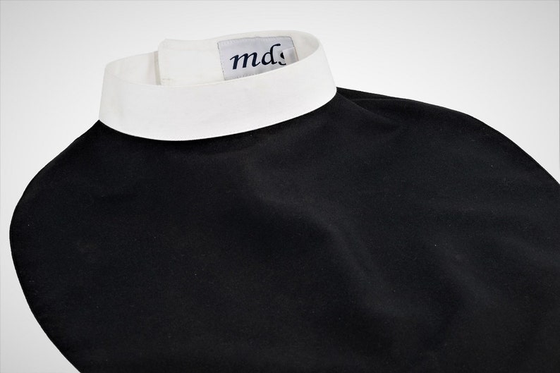 May include: A black clergy shirt with a white collar and a small white label with the text "md" on the collar.