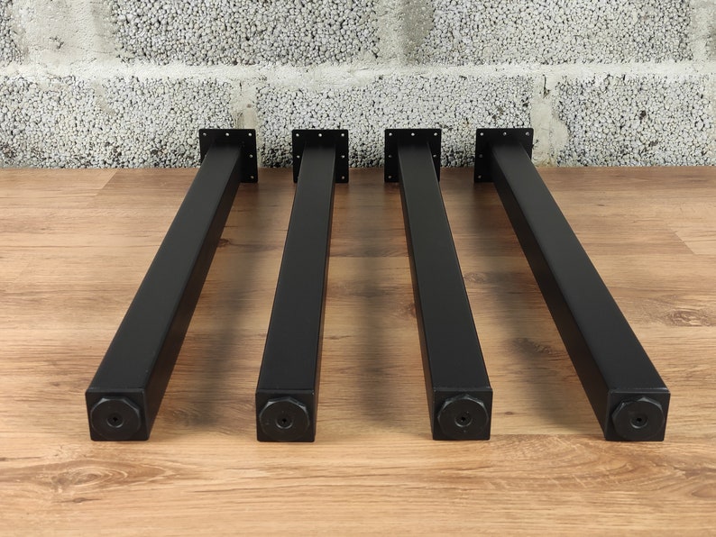 May include: Four black metal table legs with square bases. The legs are approximately 18 inches tall.