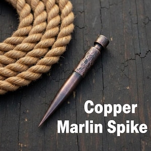 May include: A copper marlin spike with a textured handle and a pointed end. The spike is a dark copper color and rests on a dark wooden surface. The text "Copper Marlin Spike" is displayed in white.