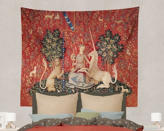May include: A tapestry featuring a red background with a white unicorn and a lion. A woman in a blue dress is seated on a cushion, holding a mirror and a unicorn's horn. The tapestry is surrounded by a border of green leaves and flowers.