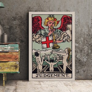 May include: A framed tarot card print featuring the Judgement card. The artwork depicts an angel with red wings blowing a trumpet, with figures below. The card has a light green background and the word "JUDGEMENT" at the bottom.