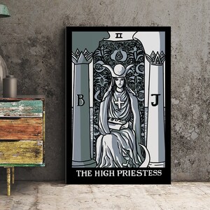 May include: A framed tarot card print of The High Priestess in shades of gray and white. The artwork features a seated figure with a cross, holding a book, with the text "THE HIGH PRIESTESS" at the bottom. The background is a textured gray.