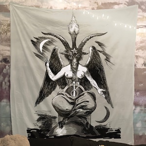 May include: A black and white tapestry featuring a detailed illustration of a winged, horned figure with a pentagram on its forehead. The figure is sitting on a sphere with a sword and snake wrapped around it. The words "Solve" and "Coagula" are written on the figure's arms.