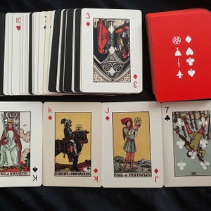 May include: A deck of tarot cards with a red box. The cards feature illustrations and symbols, including the King of Swords, Knight of Pentacles, and Page of Pentacles. The card backs are black and white.