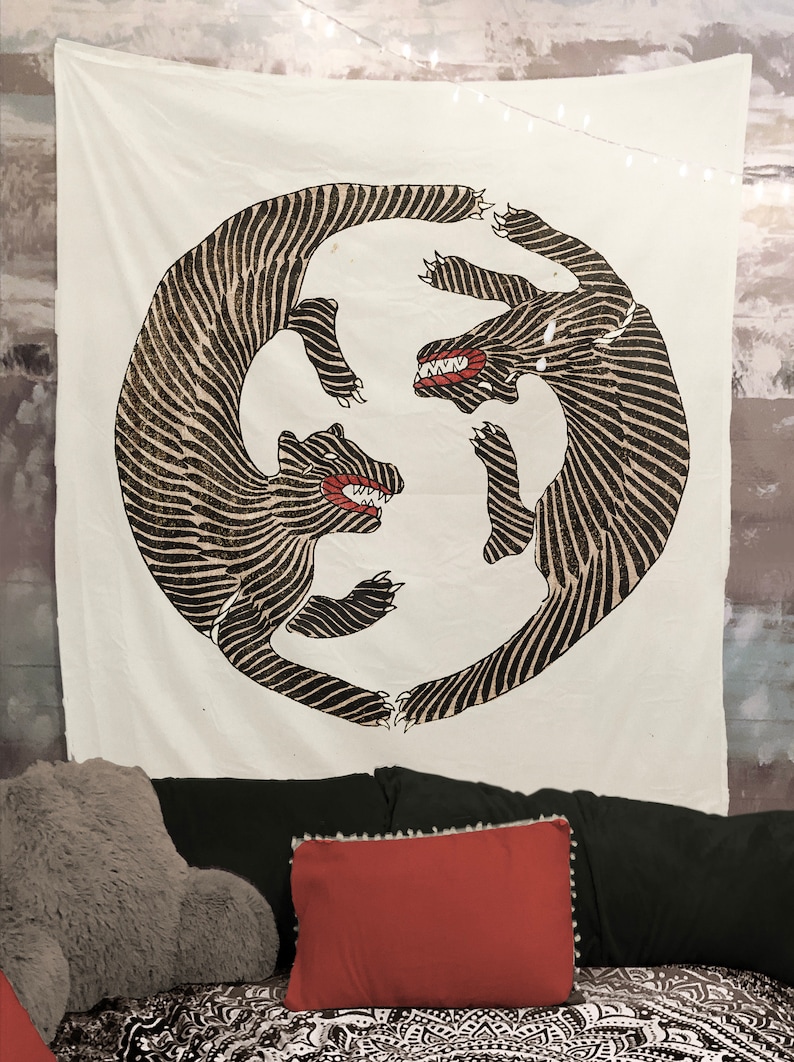 May include: A white tapestry with a black and white illustration of two stylized animals facing each other in a circle. The animals have red mouths and are drawn with a striped pattern.