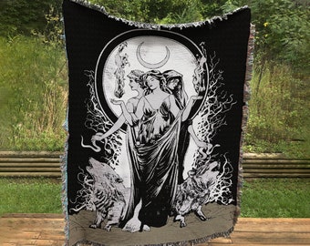 May include: Black and white woven tapestry featuring three figures with long flowing robes and a crescent moon. The figures are surrounded by trees and a snake. Two wolves are on either side of the figures.