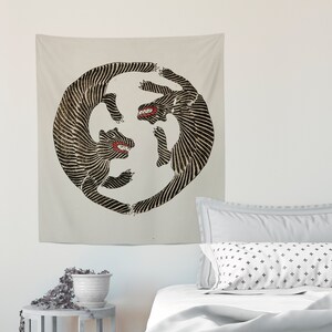 May include: A tapestry featuring a black and white circular design of two stylized animals facing each other with their mouths open. The animals are outlined in black and have a striped pattern.