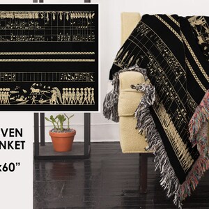 May include: Black woven blanket with a beige ancient Egyptian design. The blanket, measuring 50x60 inches, features detailed hieroglyphs and figures. It has fringed edges in multiple colors and is draped over a beige armchair.