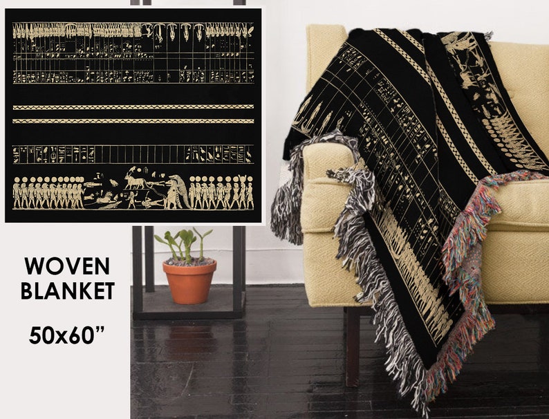 May include: Black woven blanket with a beige ancient Egyptian design. The blanket, measuring 50x60 inches, features detailed hieroglyphs and figures. It has fringed edges in multiple colors and is draped over a beige armchair.