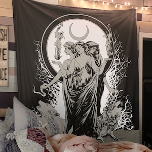 May include: A black and white tapestry featuring a stylized illustration of three women standing in a circle with a crescent moon above them. The women are surrounded by trees and wolves. The tapestry has a dark brown background.