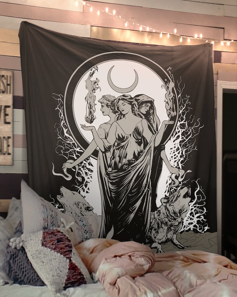 May include: A black and white tapestry featuring a stylized illustration of three women standing in a circle with a crescent moon above them. The women are surrounded by trees and wolves. The tapestry has a dark brown background.