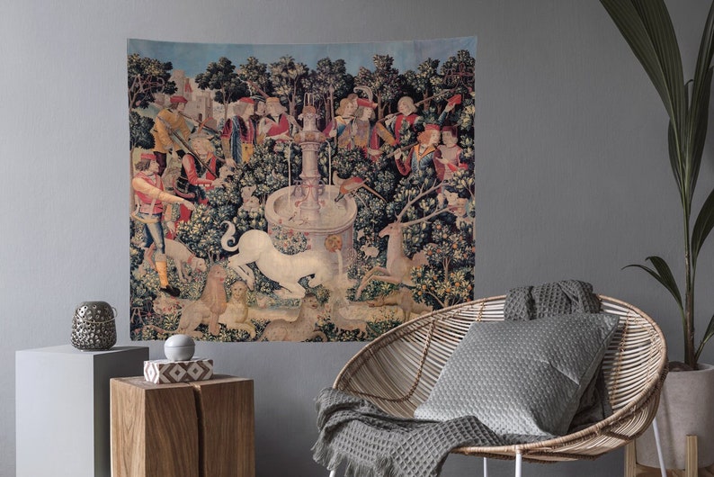 May include: A tapestry depicting a unicorn being captured by hunters in a forest setting. The unicorn is white and is surrounded by trees, flowers, and other animals. The hunters are dressed in medieval clothing and are holding spears and nets.