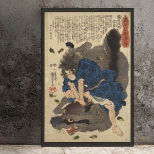 May include: Framed Japanese woodblock print depicting a figure in blue robes wrestling a large, furry beast. The artwork features detailed linework, vibrant colors, and Japanese text. The print is set against a neutral background.