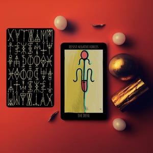 May include: Two tarot cards, one black with white symbols, the other with a yellow and green background and a red and blue figure. The card reads "RESIST NEGATIVE FORCES" and "THE DEVIL". The image includes a gold sphere, a wooden block, and white spheres on a red surface.