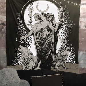 May include: Black and white tapestry featuring a triple goddess figure with a crescent moon above her head. She is surrounded by wolves and a snake. The tapestry has a dark background and a white circle around the goddess.