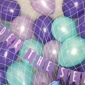 A fishing net holding a variety of balloons in purple, pearl lilac, and pearl mint.