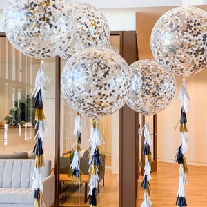 Five 3ft clear balloons stuffed with tissue confetti in the colors white, gold, and black, with matching tassel tail.