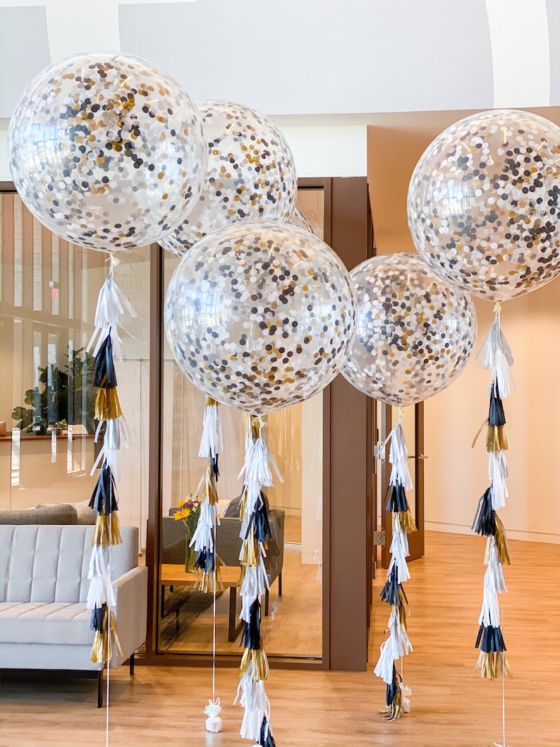 Five 3ft clear balloons stuffed with tissue confetti in the colors white, gold, and black, with matching tassel tail.