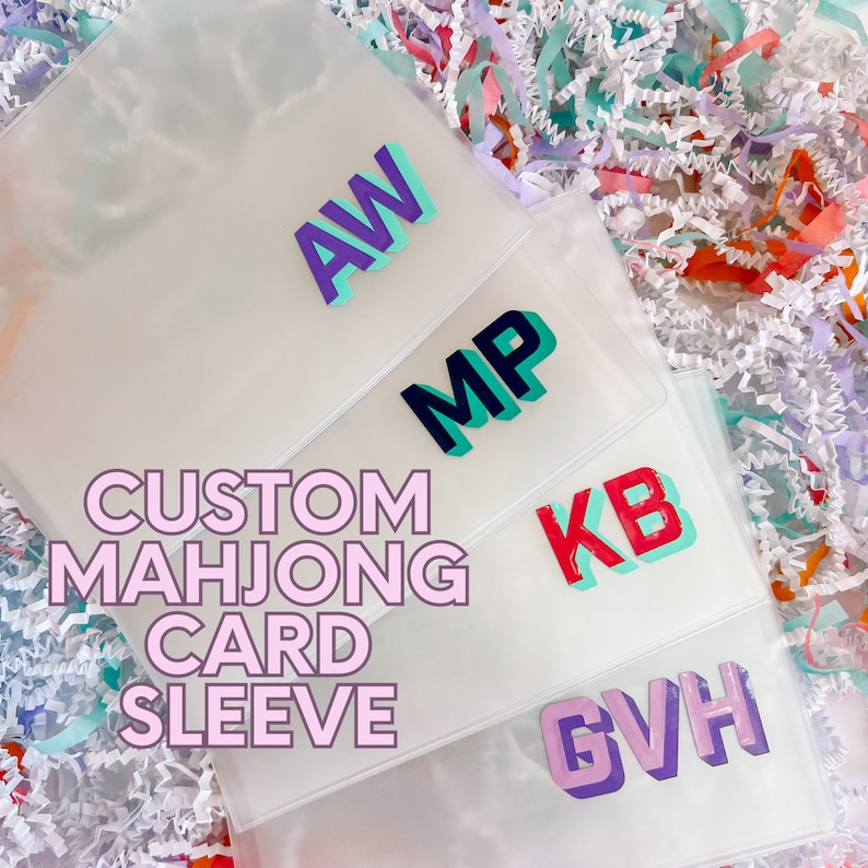 May include: Four clear plastic sleeves with custom initials in colorful 3D letters. The sleeves are for mahjong cards. The text "CUSTOM MAH JONG CARD SLEEVE" is written in pink letters on the front of the sleeves.