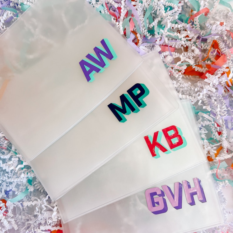 May include: Four clear plastic pouches with different colored letters on each. The letters are in a 3D style and spell out "AW", "MP", "KB", and "GVH".