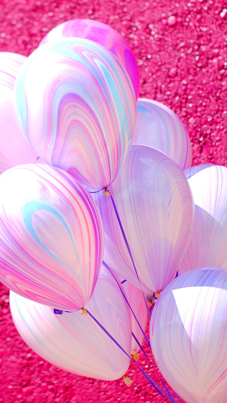 Bundle of 11" latex balloons with purple marble design in front of a hot pink wall.