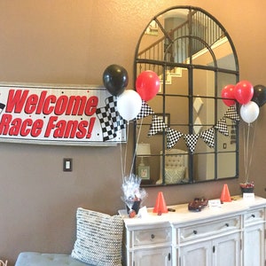 A racecar themed party with red, black, and white balloons floating with helium