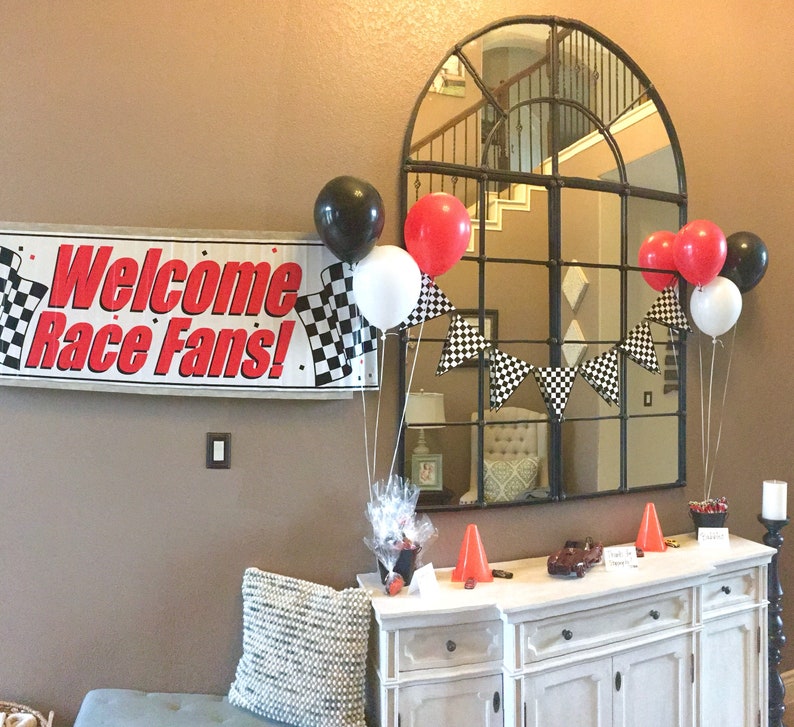 A racecar themed party with red, black, and white balloons floating with helium