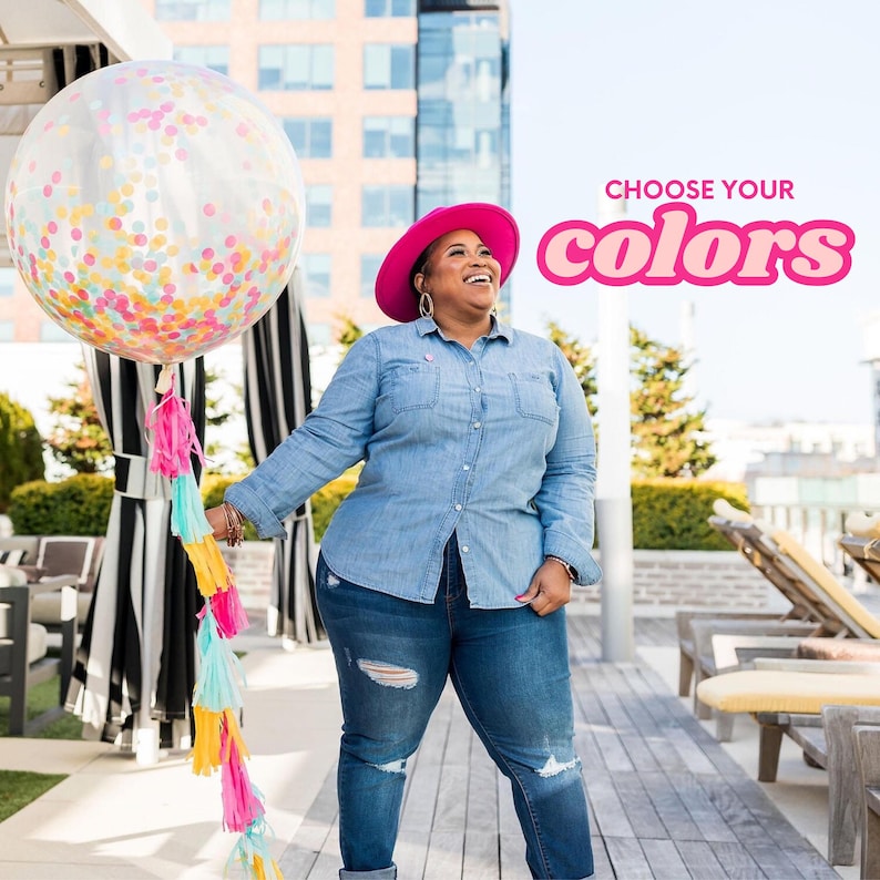 Puede incluir: Una mujer con un sombrero rosa y una camisa vaquera azul sostiene un gran globo transparente con confeti de colores en su interior. El globo est&aacute; sujeto a una larga cuerda de borlas de colores. El texto "CHOOSE YOUR COLORS" est&aacute; en letras rosas sobre un fondo blanco.