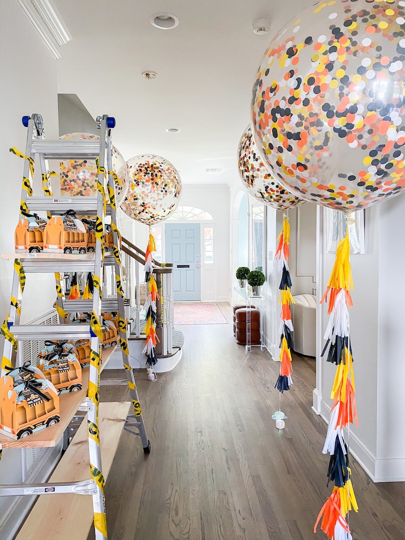 Construction themed 3ft clear balloons stuffed with tissue confetti in the colors white, orange, black, and yellow with matching tassel tail.