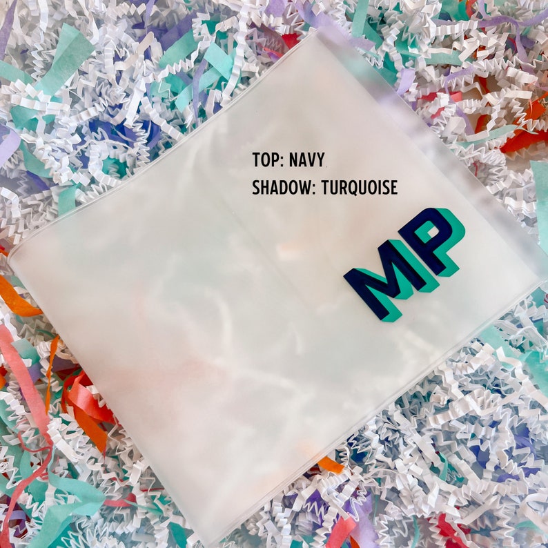 May include: A clear plastic envelope with the text "TOP: NAVY SHADOW: TURQUOISE" and the letters "MP" in turquoise with a navy blue outline.